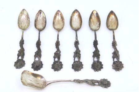 Conjunto de seis colheres de chá e pá de açúcar em prata recortada com relevos nos cabos em forma de flores.